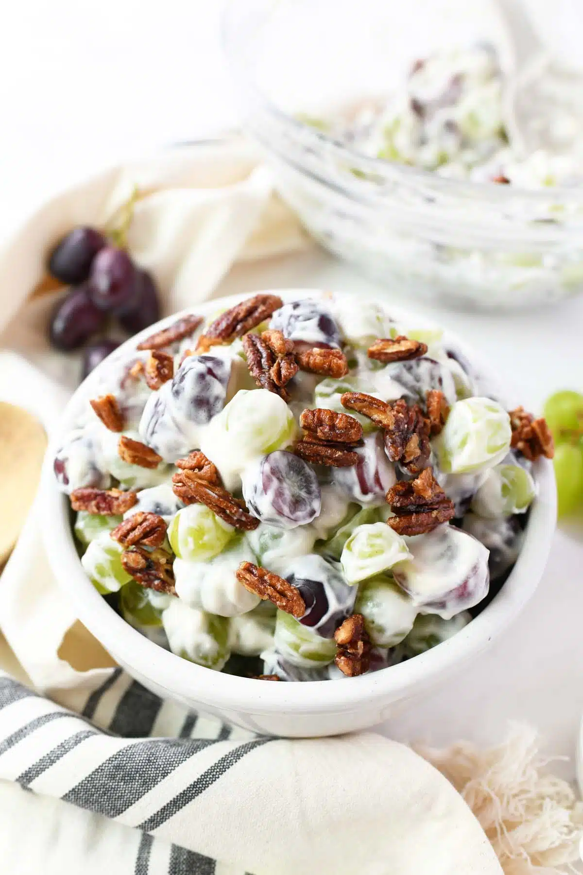 Colorful grape salad with pecans in a white bowl.