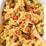 A wooden spoon inside sausage and feta pasta.