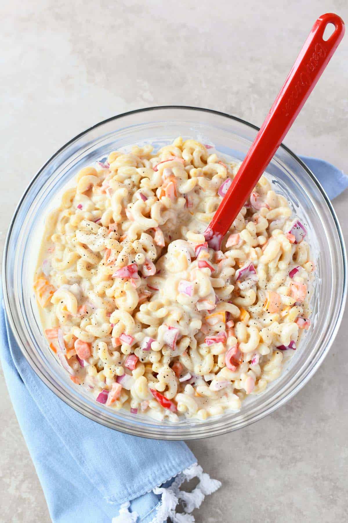Sweet Macaroni Salad in a bowl with a red spoon.