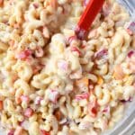 A red spoon in macaroni salad.