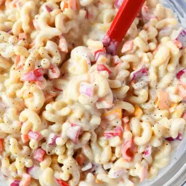 A red spoon in macaroni salad.