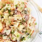 Hawaiian pasta salad in a glass bowl with a wooden spoon nearby.