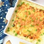 A square crock with cheesy corn dip inside.