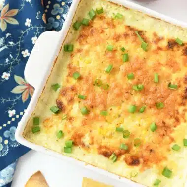 A square crock with cheesy corn dip inside.