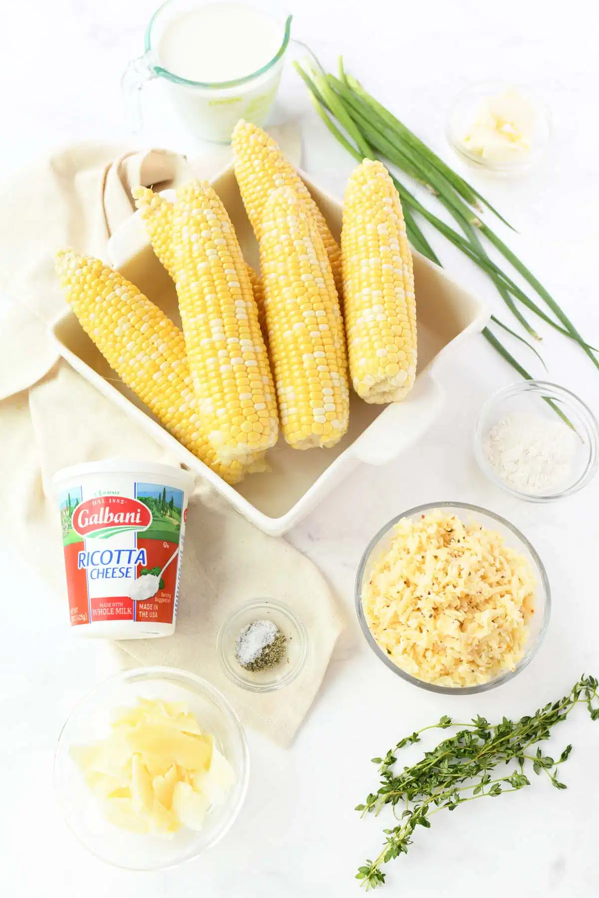 Grilled corn dip ingredients on a white table.