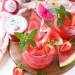 A glass of pink, icy, frozen margaritas with a mint leaf.