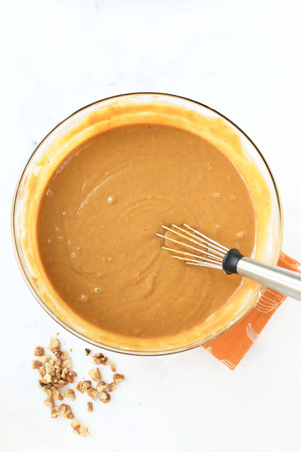 Wet pumpkin batter in a bowl with a whisk.