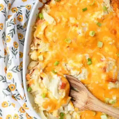 A wooden spoon with cheesy crab casserole on it.