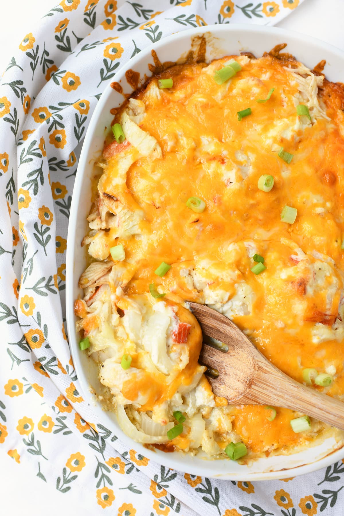 A wooden spoon with cheesy crab casserole on it.