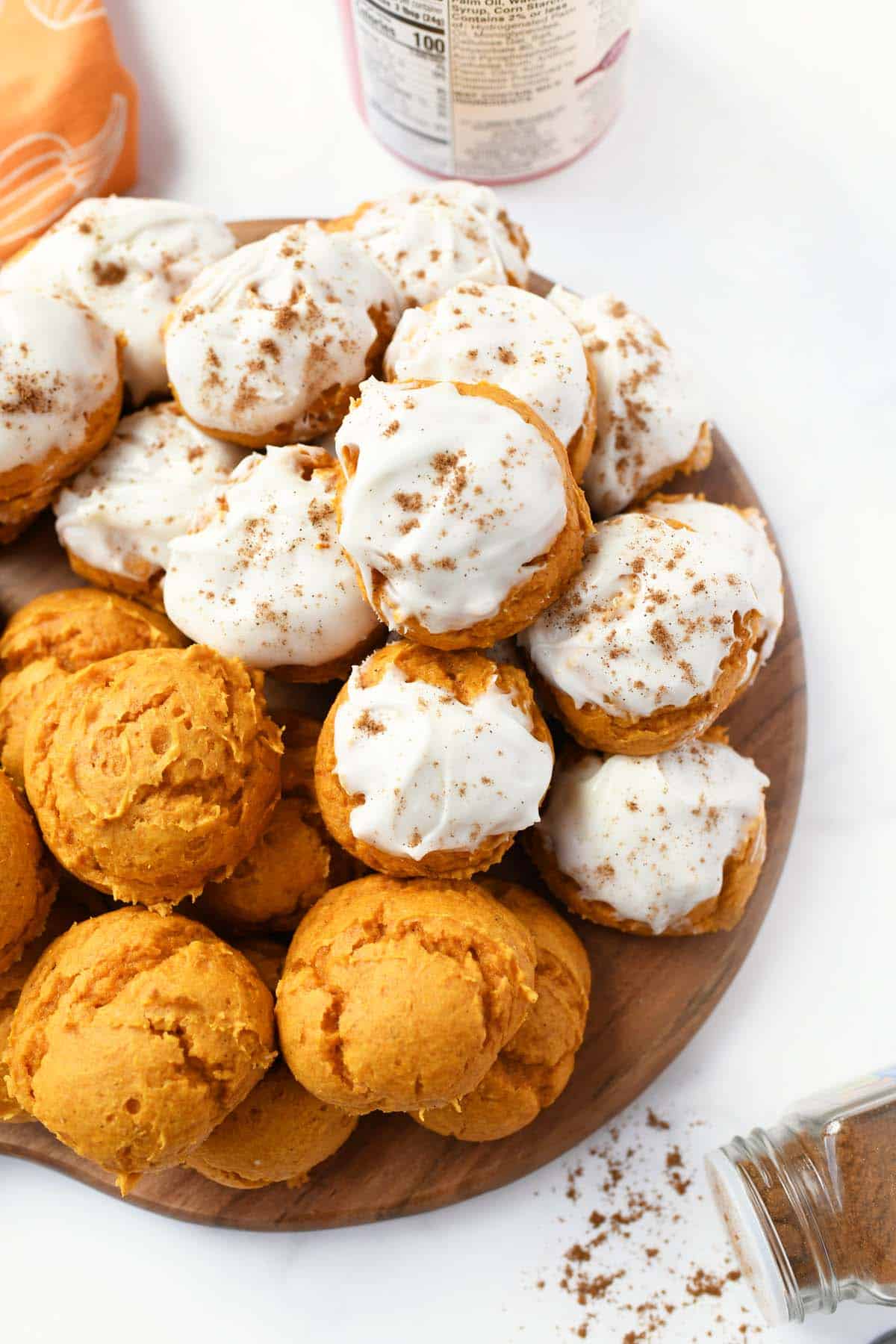 Iced pumpkin cookies on a wooden tray.