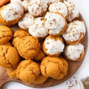 Iced and un-iced pumpkin cake mix cookies on a wooden tray.