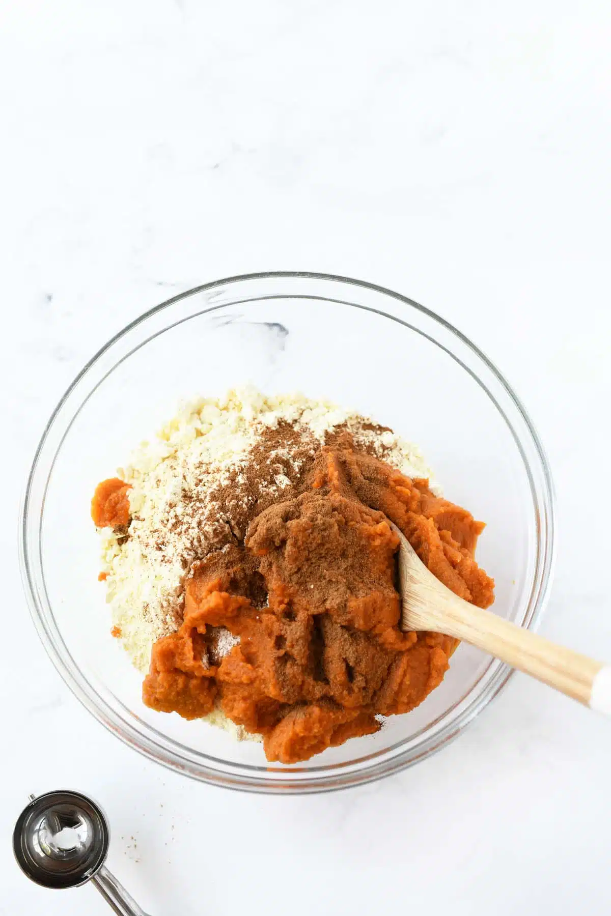 A glass bowl with canned pumpkin and cake mix inside.
