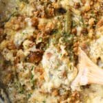 Golden brown chicken and stuffing on a wooden spoon.