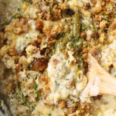 Golden brown chicken and stuffing on a wooden spoon.