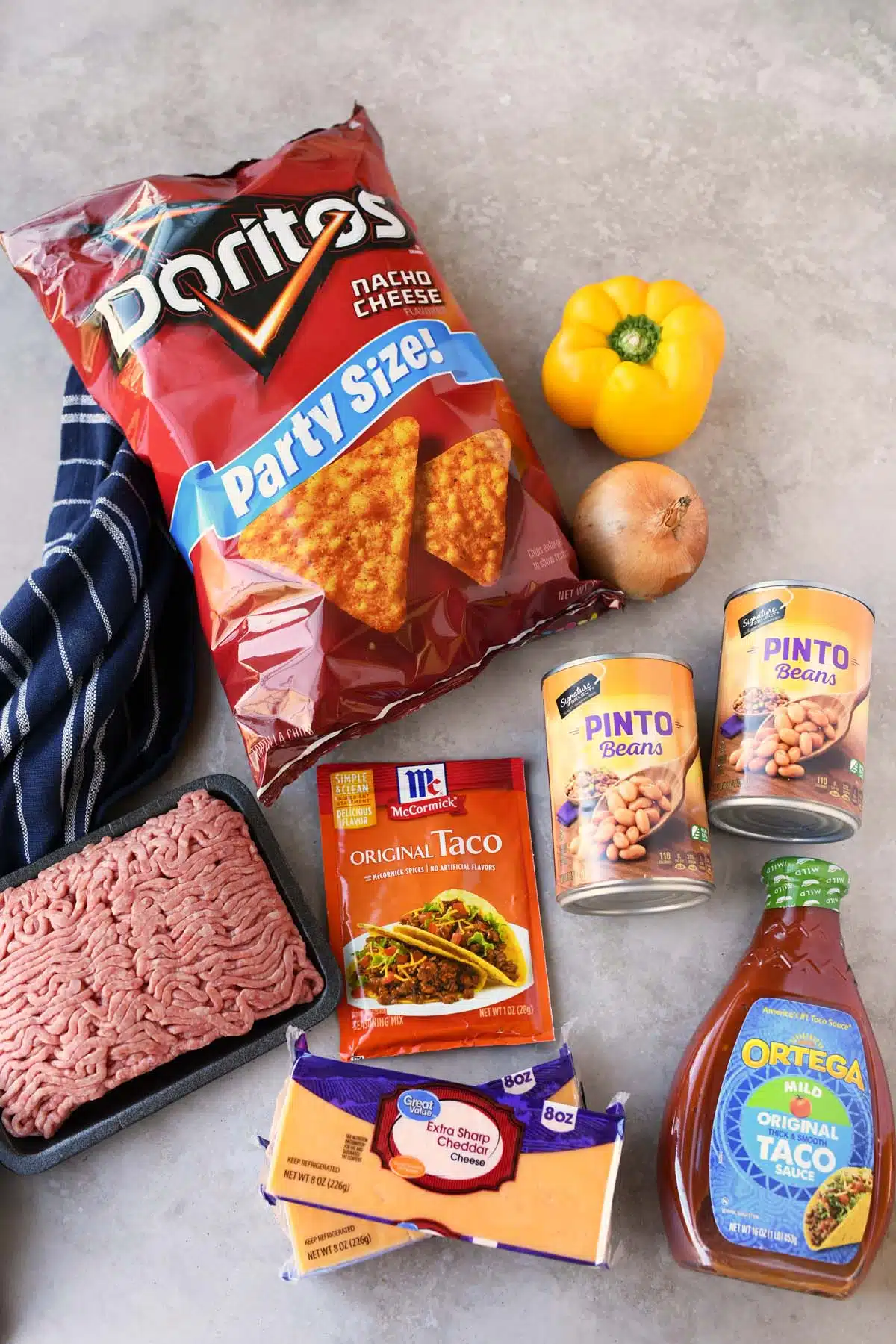 Ingredients for Dorito Pie on a stone surface with a blue, striped napkin. 