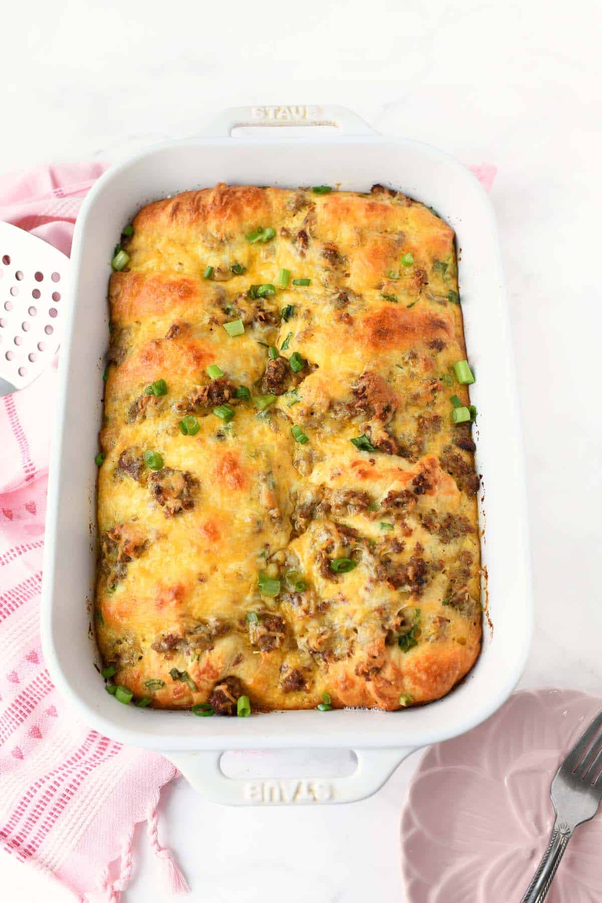A baked sausage crescent casserole in a white baking dish.