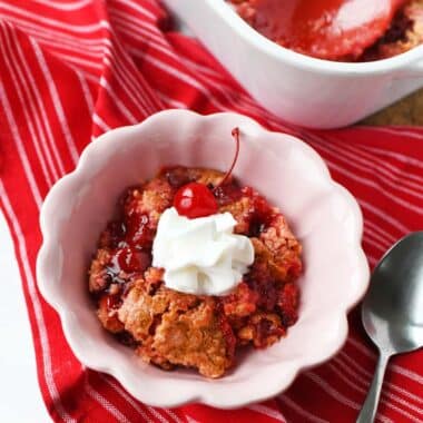 A pink bowl with strawberry cherry dump cake inside.