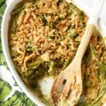 Green Bean Casserole in a white oval dish with a spoon.