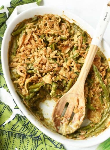 Green Bean Casserole in a white oval dish with a spoon.