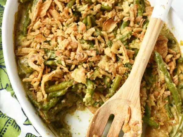 Green Bean Casserole in a white oval dish with a spoon.