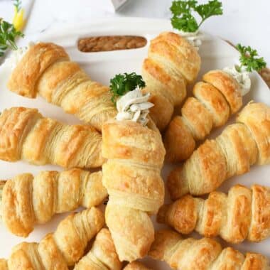 Puff pastry carrot appetizers on a white tray.