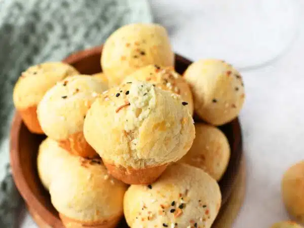 A wooden bowl of mini cream cheese stuffed biscuit bites.