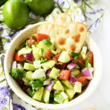 A small bowl of cucumber salsa with heart-shaped crackers.