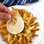 Onion petals and sauce in a hand.