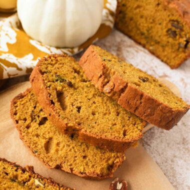 Slices of pumpkin zucchini bread on a harvest themed table.