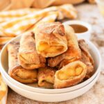 A white plate of apple pie egg rolls.