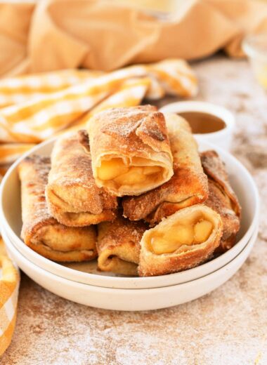 A white plate of apple pie egg rolls.