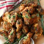 A parchment-lined platter with golden-brown garlic parmsan wings and ranch.