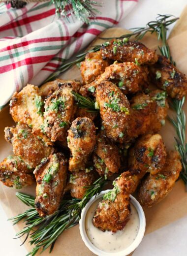 A parchment-lined platter with golden-brown garlic parmsan wings and ranch.
