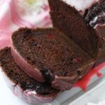Pink iced, sliced chocolate cherry maraschino cake.