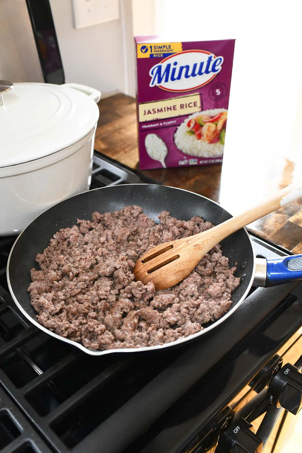 A blue frying pan with ground beef inside.