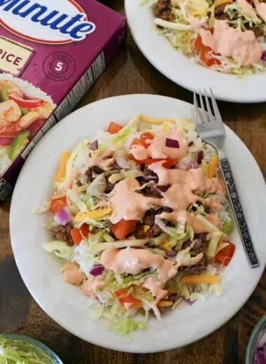 A loaded cheeseburger bowl with a silver fork.