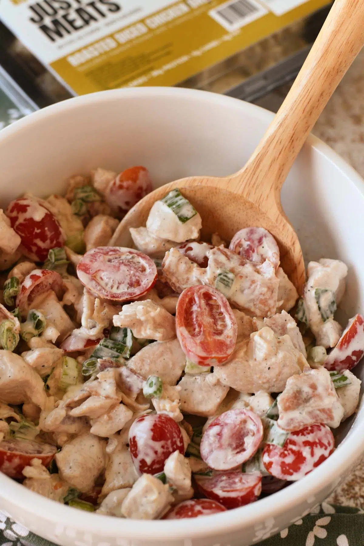 An up-close shot of BLT chicken salad in a wooden spoon.