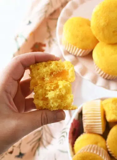 A hand holding a split in half peach pie cupcake.