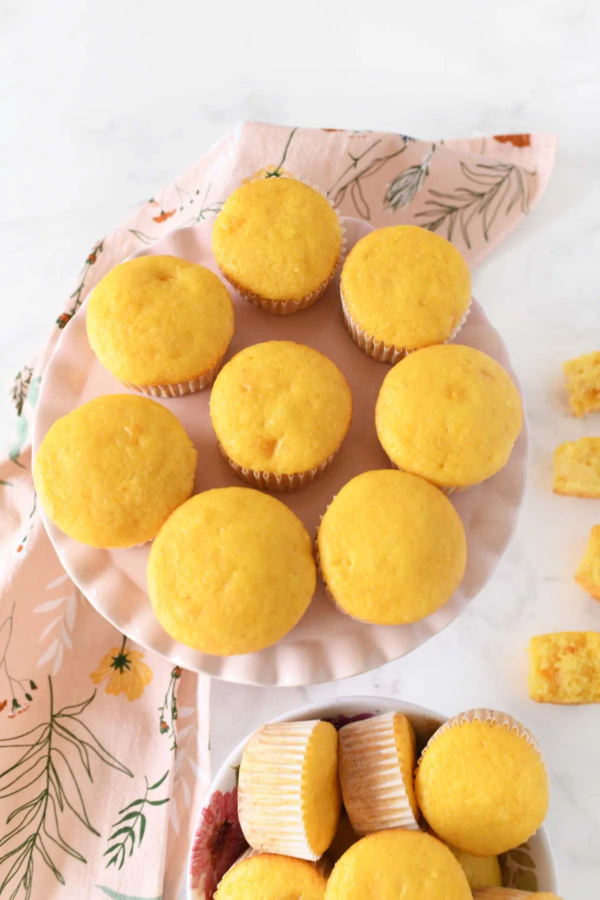 Yellow peach cupcakes on a pink cake stand.