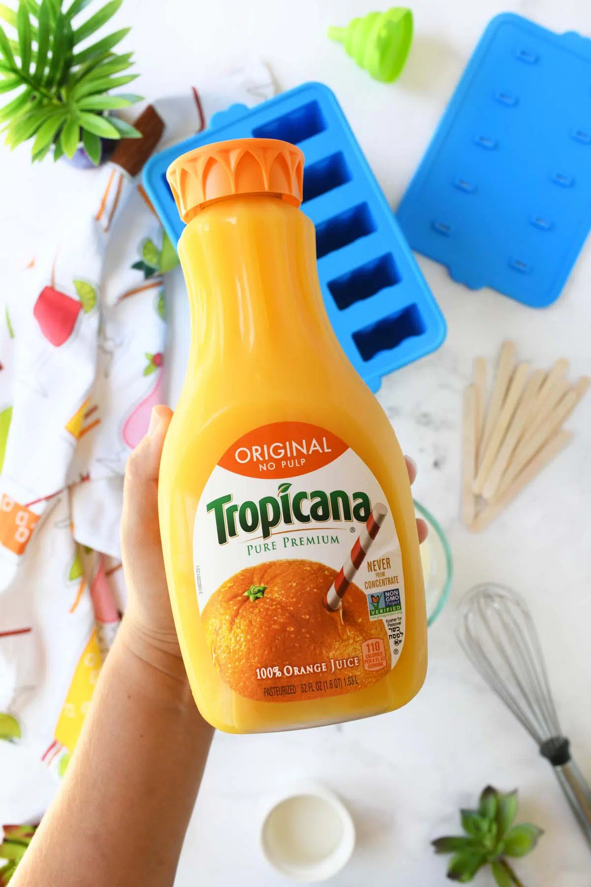 A hand holdign a bottle of Tropicana Orange Juice.