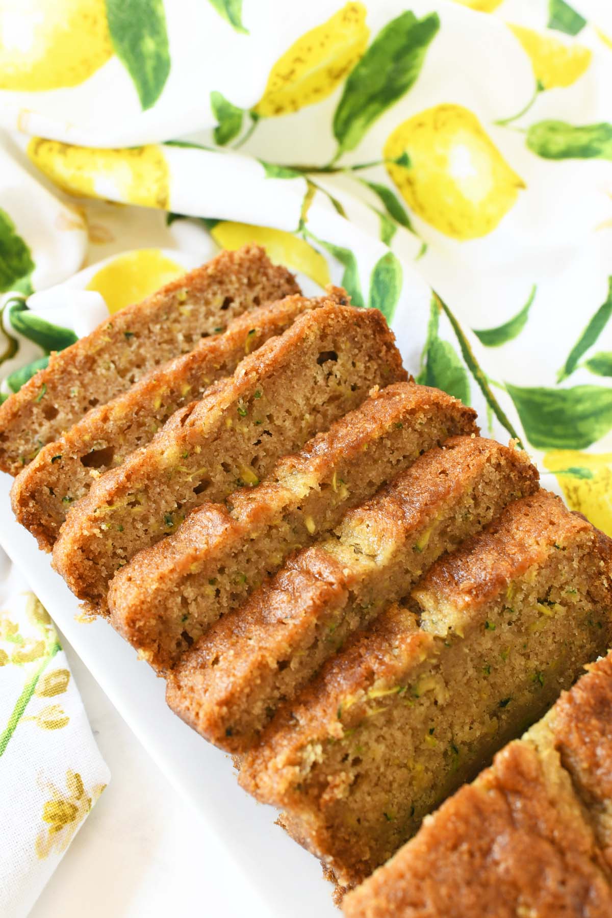 Sliced zucchini bread near a yellow lemon napkin.