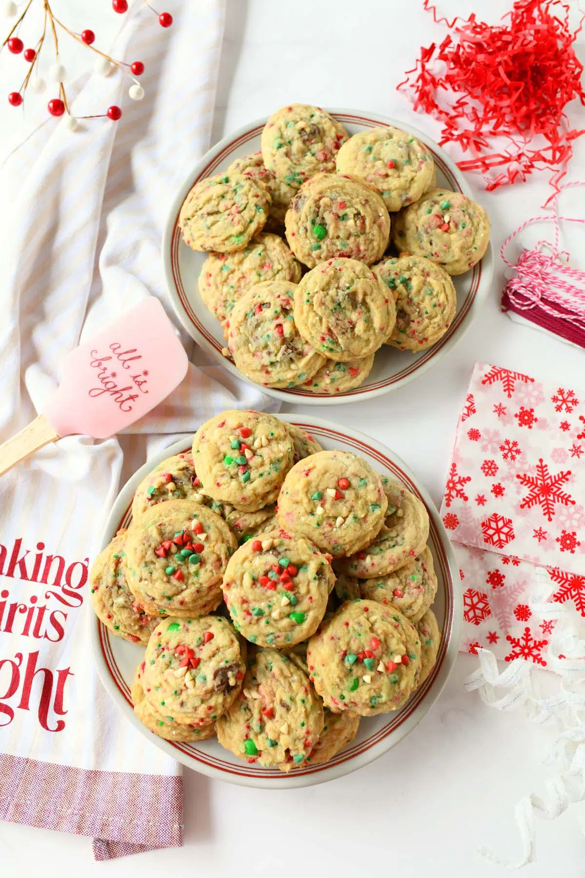 Two plates of red, white, and green cookies with a spatula and napkins.
