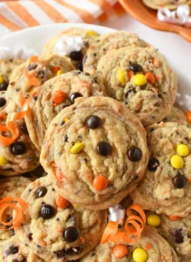 A plate of baked yellow, orange, and brown candy cookies on a platter.