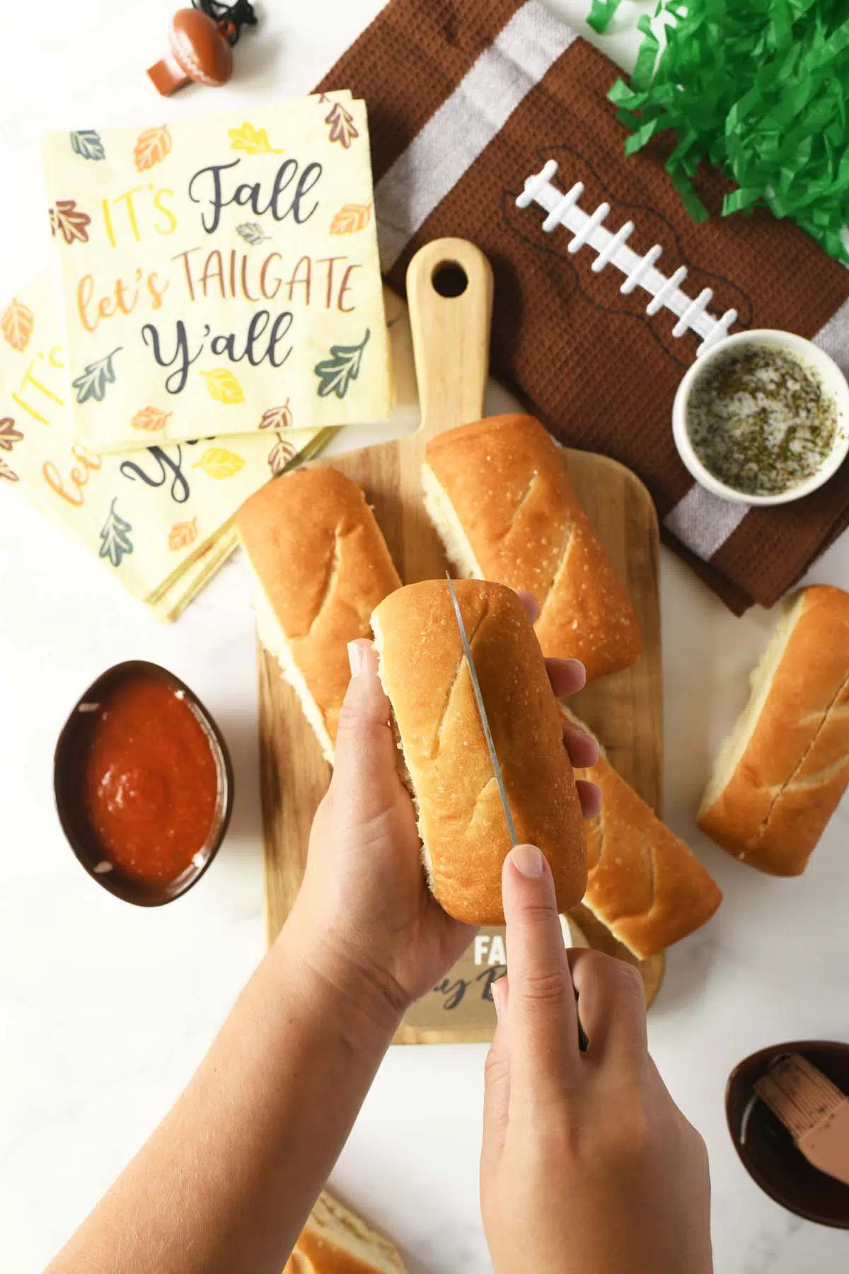 A white hand slicing a mini sub roll.