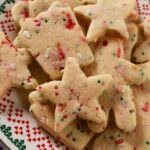 Up close shot of holiday sprinkle cut out cookies on a Christmas plate.
