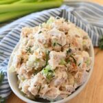 Turkey salad in a white dish with a blue, striped napkin and green celery.