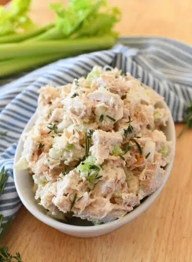 Turkey salad in a white dish with a blue, striped napkin and green celery.