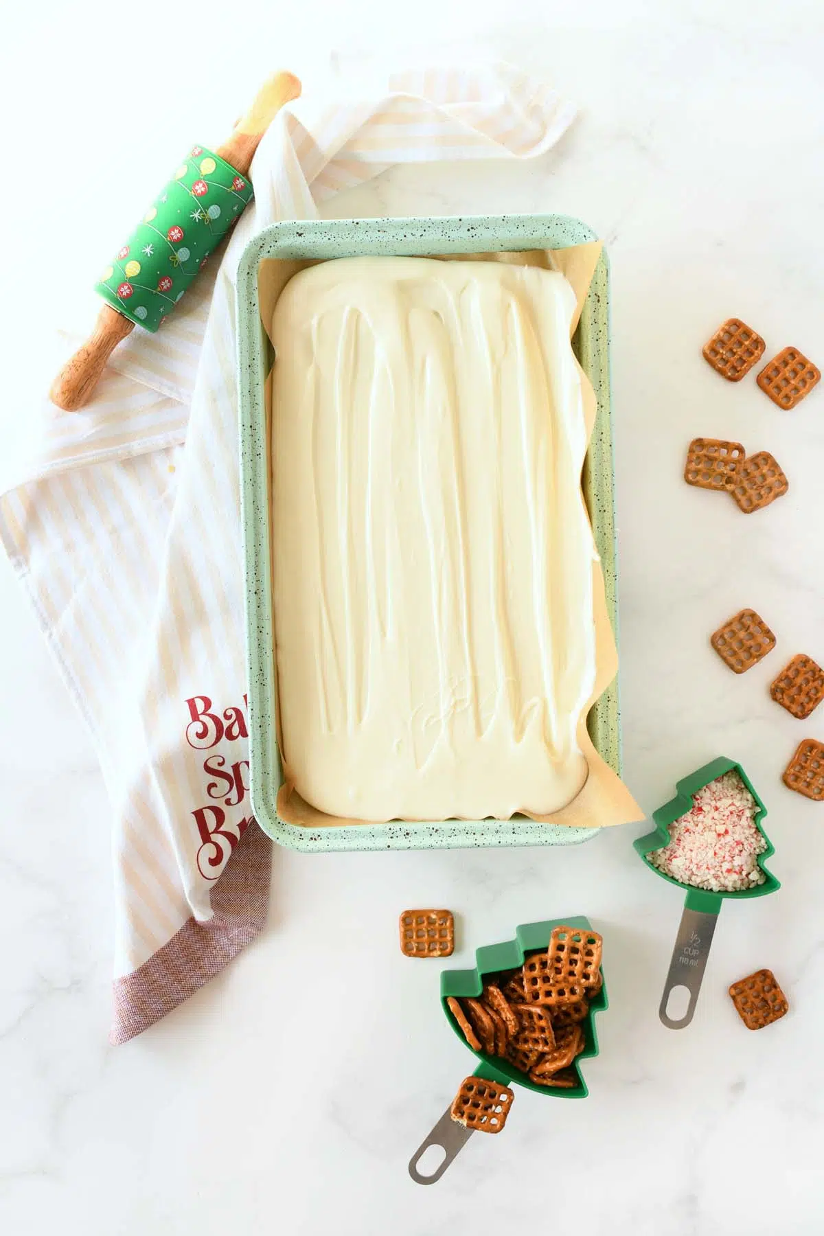 White chocolate bark spread on a blue, parchment-lined pan with ingredients nearby.