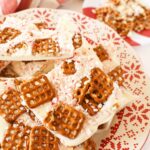 A plate of white chocolate pretzel bark on a red, scalloped plate.