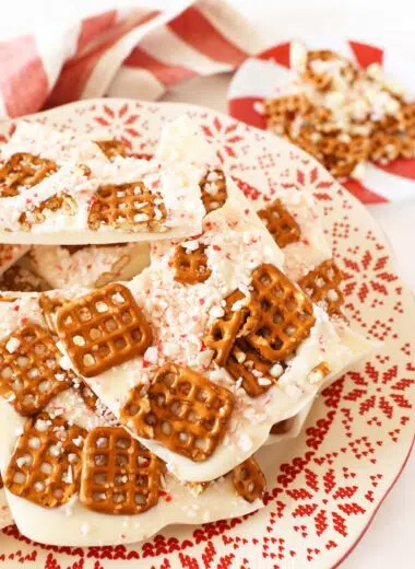 A plate of white chocolate pretzel bark on a red, scalloped plate.